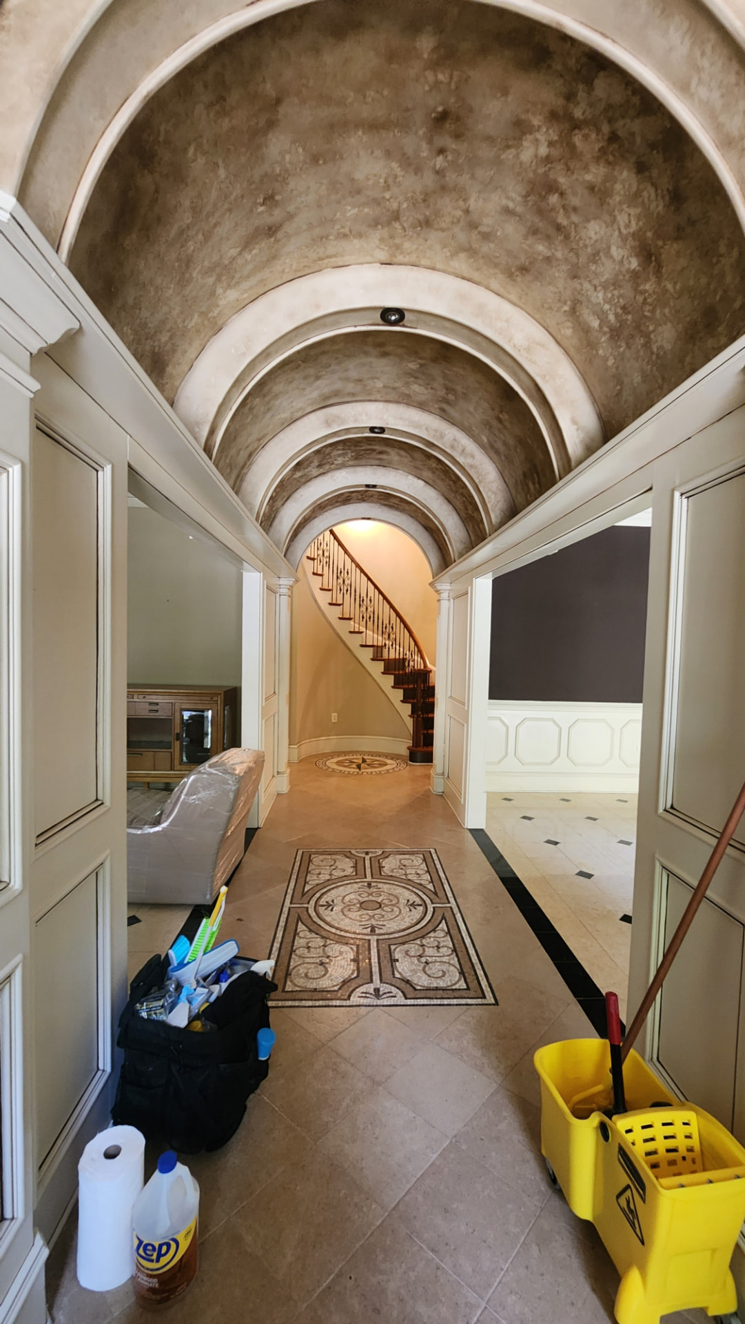 Arched hallway with cleaned mosaic tile inlay floor and cleaning equipment ready