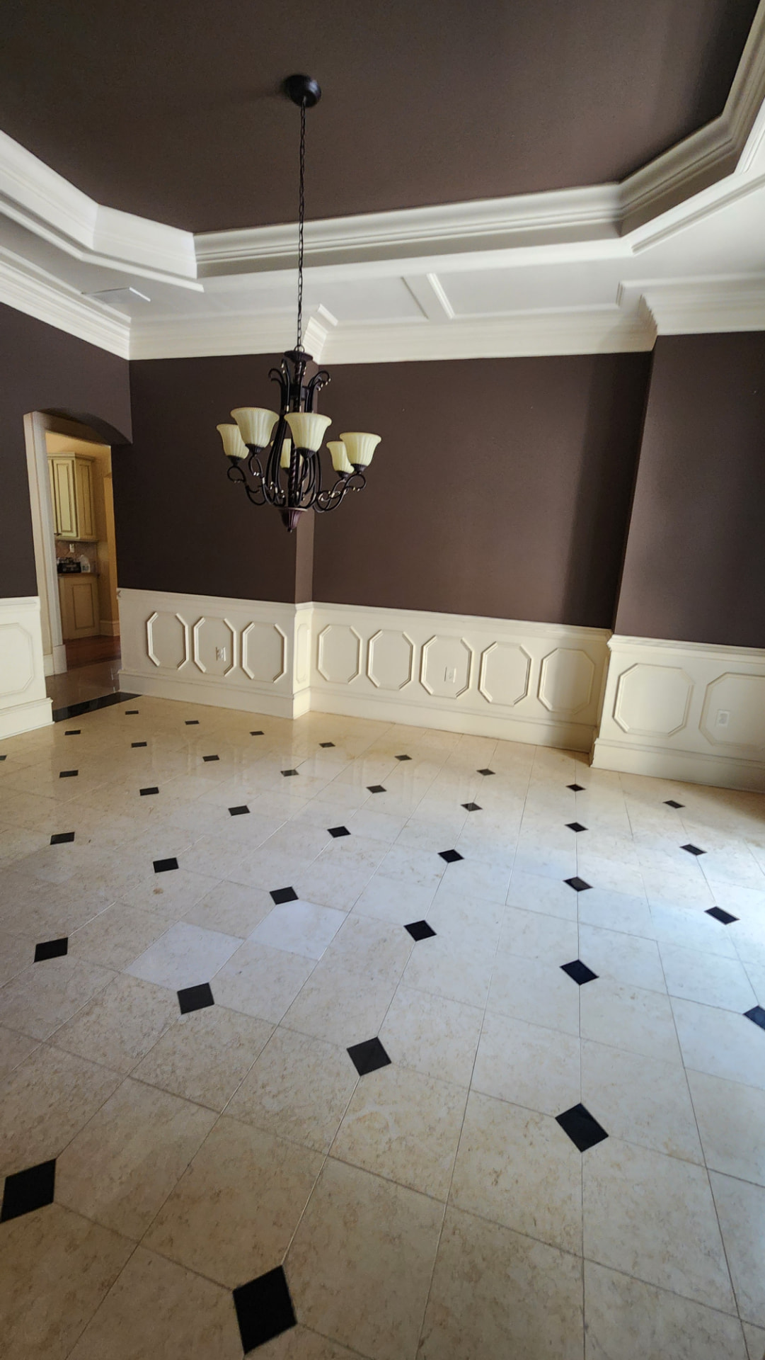 Dining room with spotless tile floors, clean wainscoting, and dusted chandelier